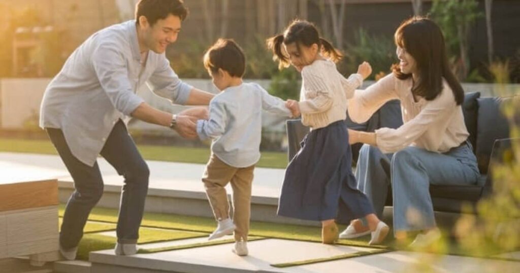 4 人家族が、明るい芝生の環境で晴れた日を楽しんでいます。両親は笑顔で 2 人の幼い子供と遊んでいます。女性は娘のバランス感覚を助けながら、初心者向けのヒントも提供しています。楽しい雰囲気は、家族の気楽な絆と冒険心を反映しています。.